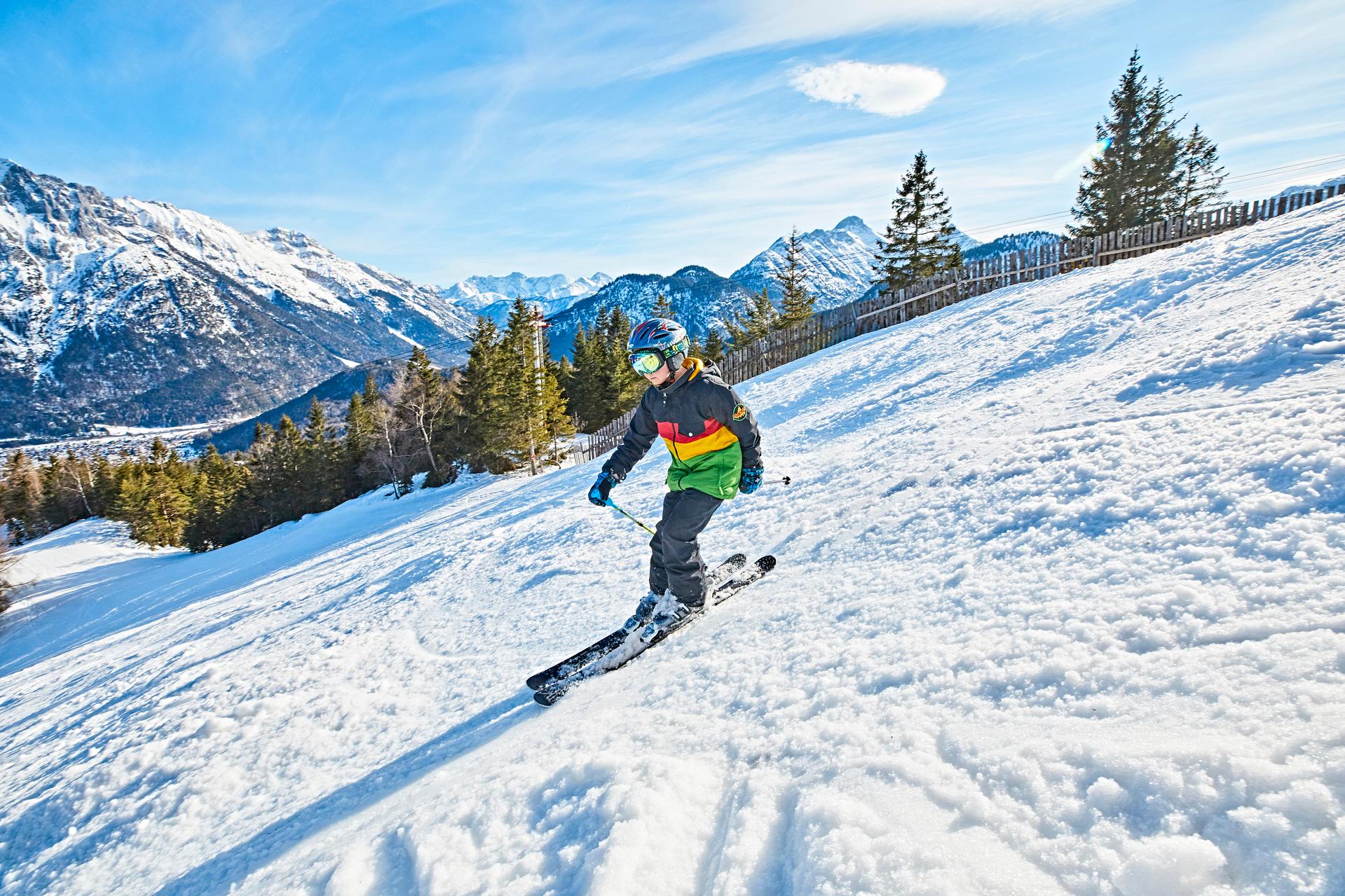 Child skiing downhill in a technical winter jacket and helmet