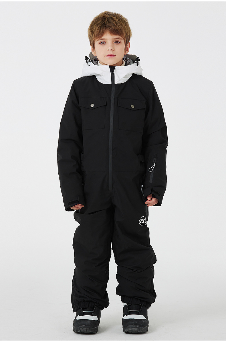 Boy wearing the black one-piece ski suit with white-lined hood and zippered side pockets, front view