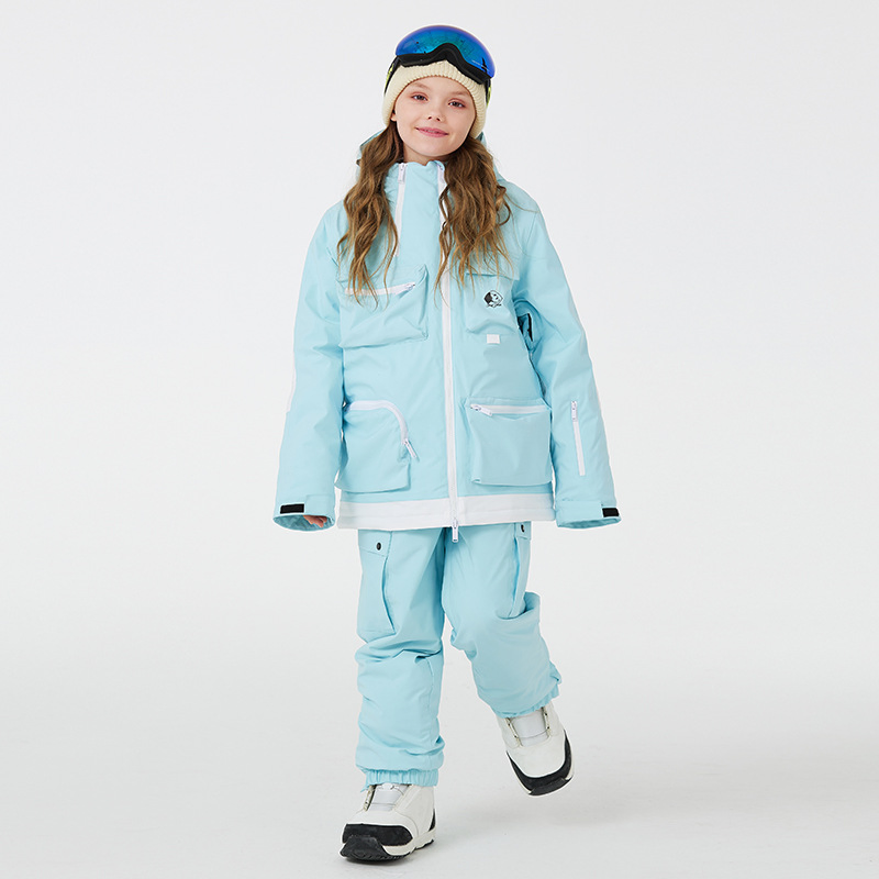 Girl wearing the light blue two-piece ski set with cargo pockets, jacket and pants, front view