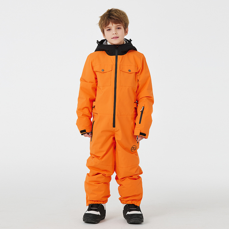 Boy wearing the orange ski jumpsuit with snap-flap chest pockets and elastic leg cuffs, front view