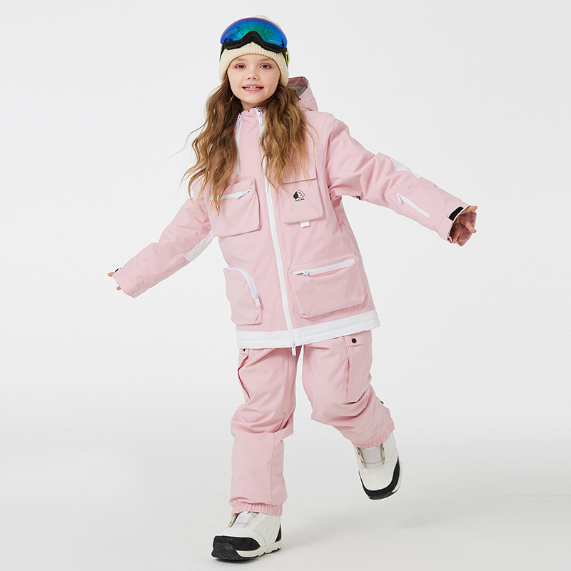 Girl mid-stride in the pink two-piece snowboard set with cargo pockets, jacket and pants