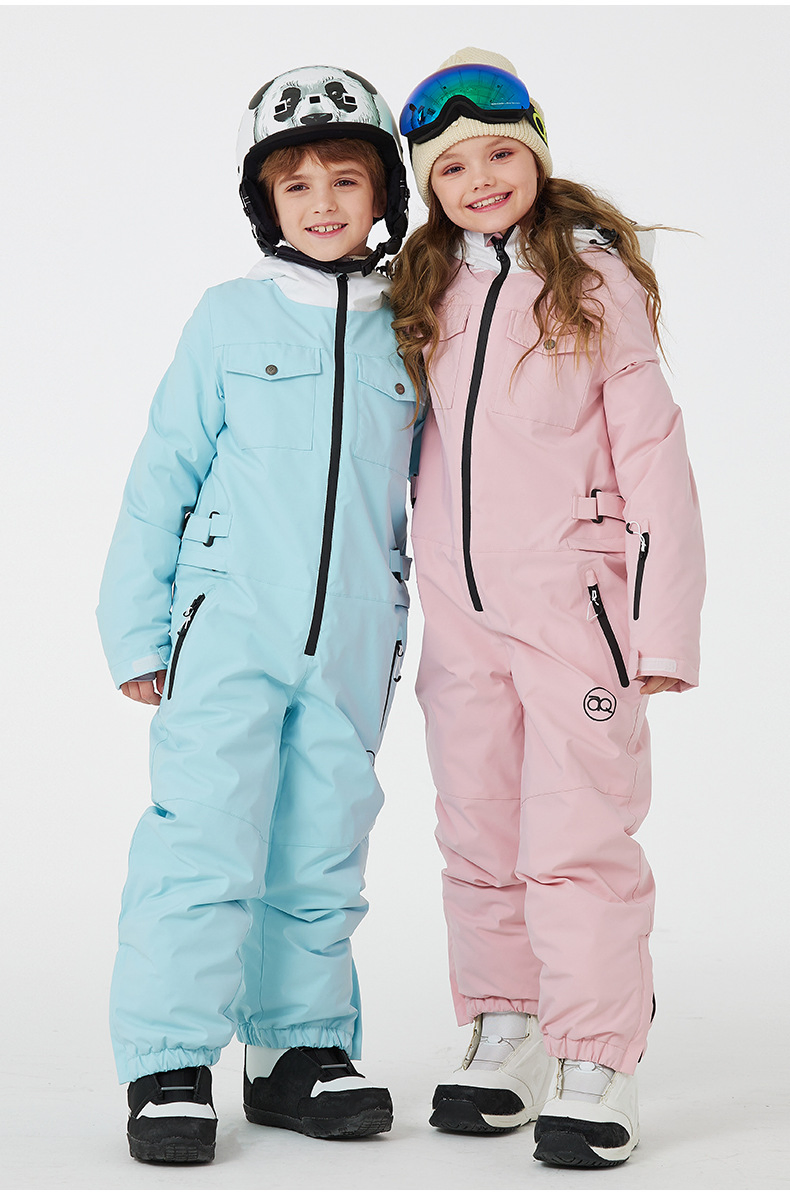 Boy in the ice blue ski jumpsuit and girl in the pink ski jumpsuit with ski helmets, side by side