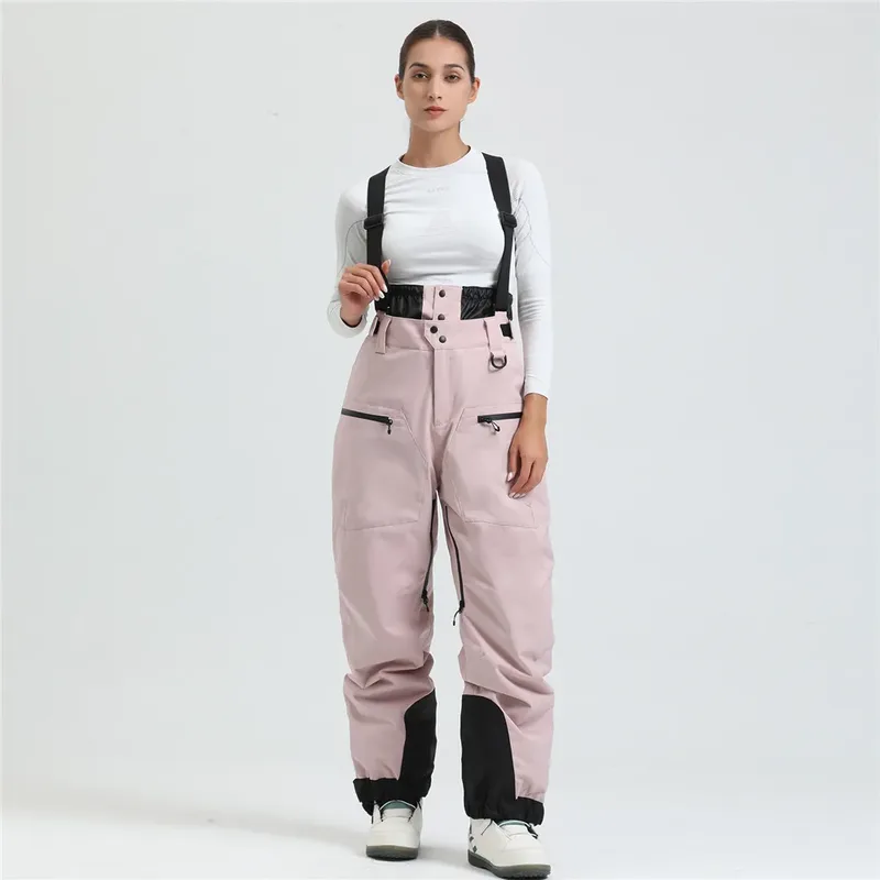 Women's ski bib pants in Light Pink — adjustable suspenders and a shaped fit, worn by a model