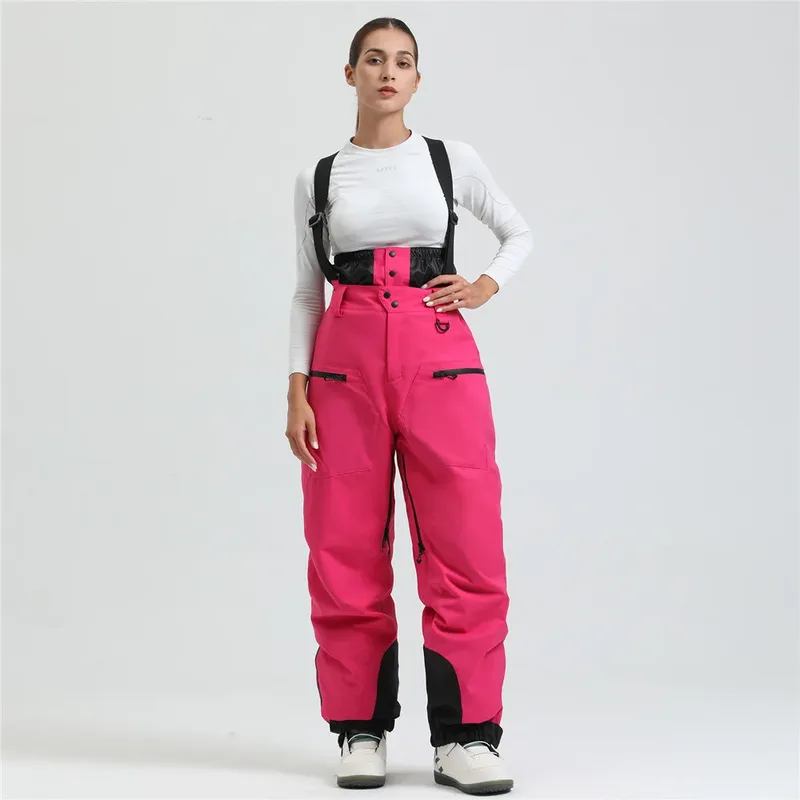 Women's ski bib pants in Rose Red — adjustable suspenders and a shaped fit, worn by a model